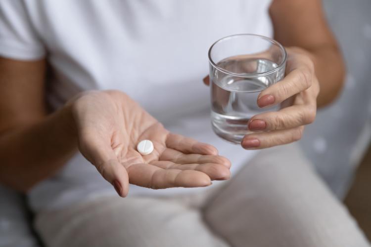 Woman holding a pill and glass of water