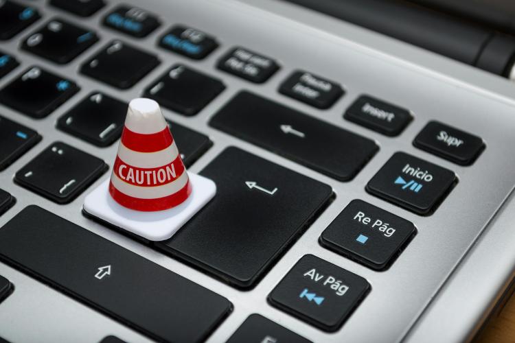 Tiny white and orange caution cone placed on top of a keyboard