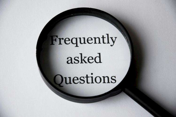 Black magnifying glass positioned over the text 'Frequently Asked Questions'