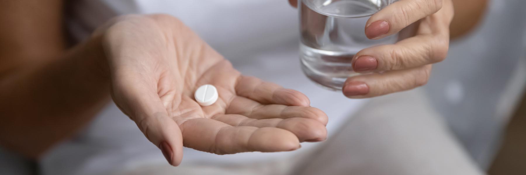 Woman holding a pill and glass of water