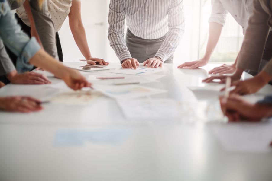 Low angle view of hands of multiracial group of people working with documents on a table